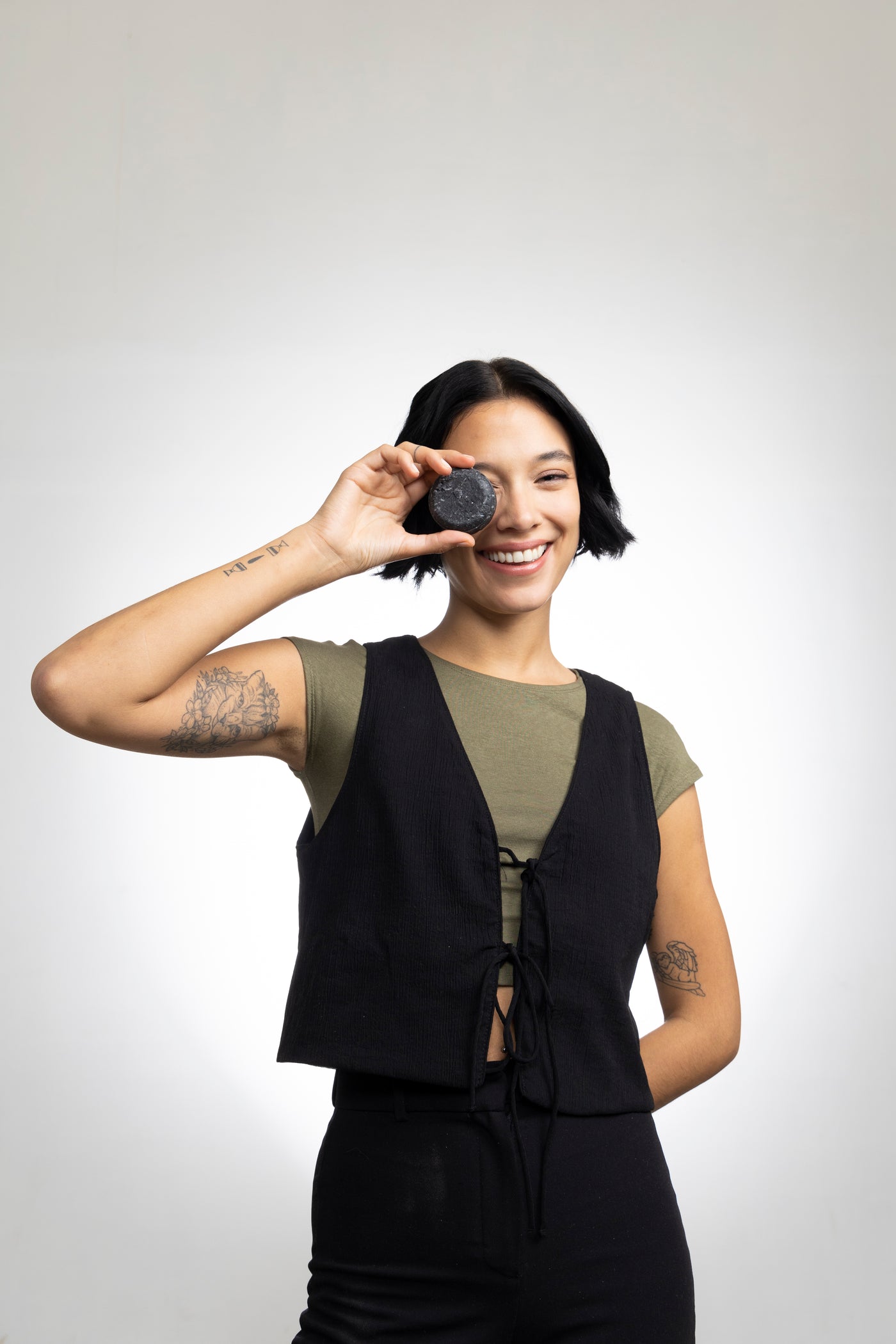 Modelo sonriendo con un shampoo en barra Natural Detox frente a su ojo